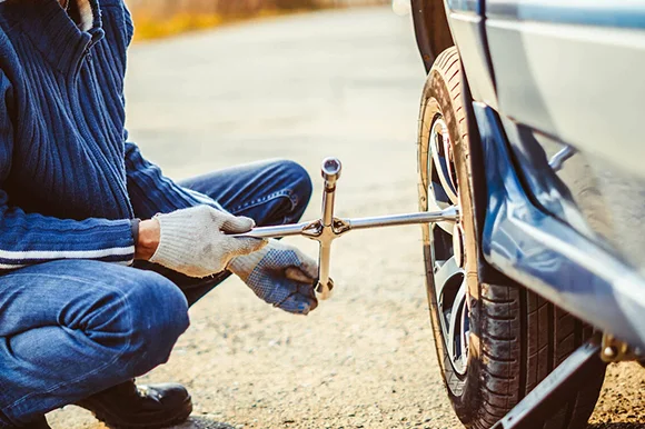 Technician replacing a car tire with a new one during an on-site installation service in Sacramento, CA.