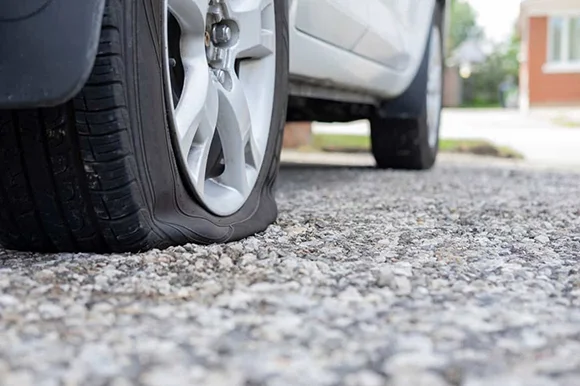 Close-up of a flat tire on a car ready for repair, representing trusted tire repair services in Folsom, CA.