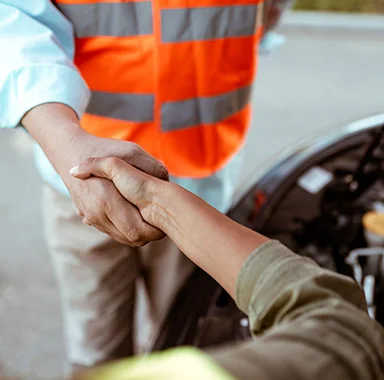 Close-up of a professional shaking hands with a driver, symbolizing reliable roadside assistance in California.
